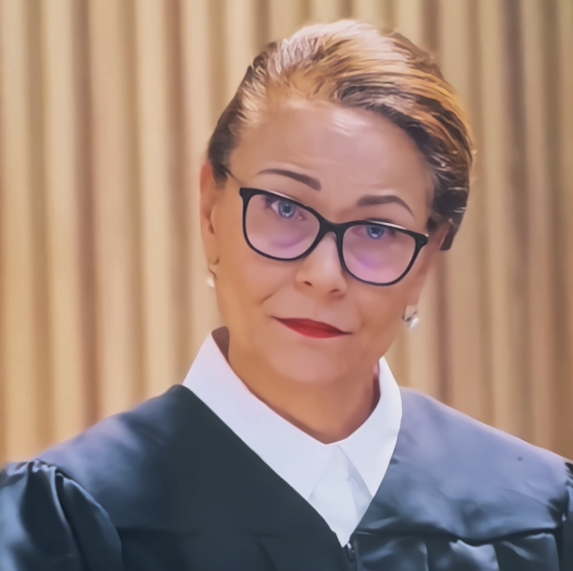 Marie Finch portraying a judge in a black robe and glasses